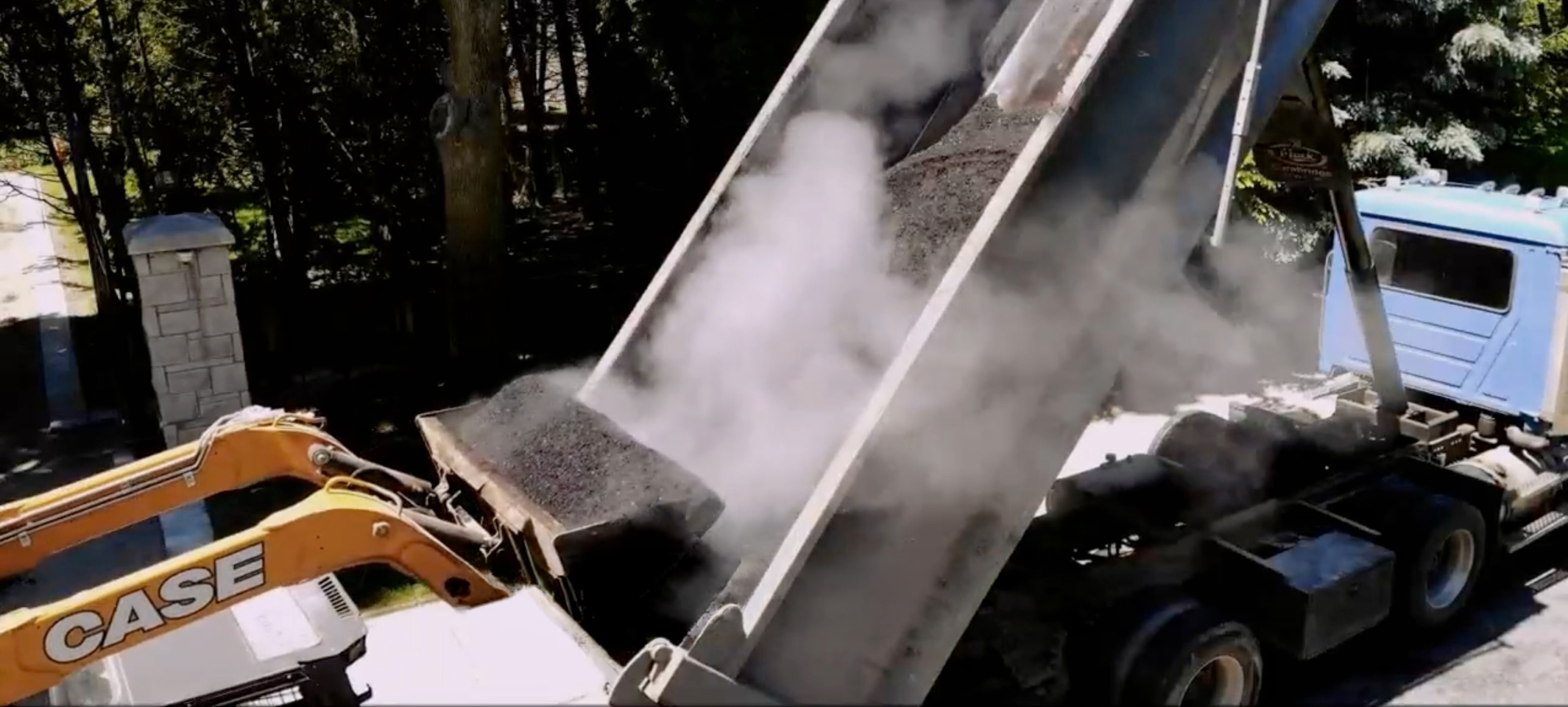Dump truck unloading hot asphalt with heavy equipment